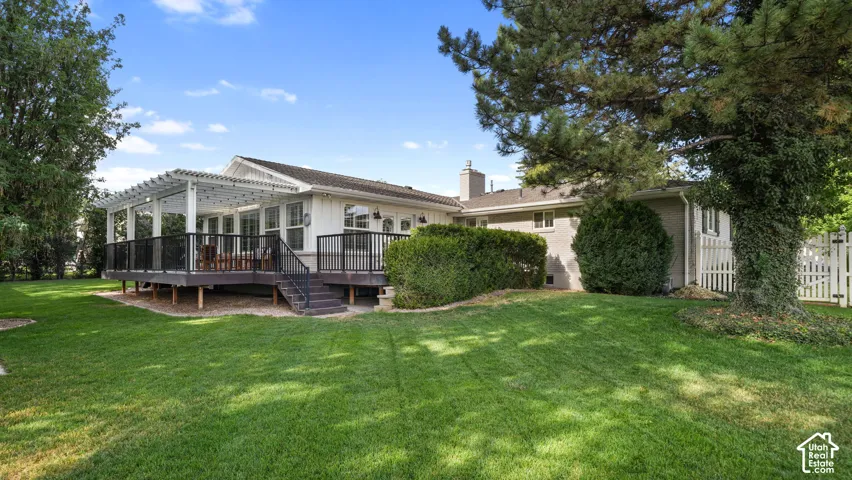 Expansive green lawn with mature trees and a white picket fence