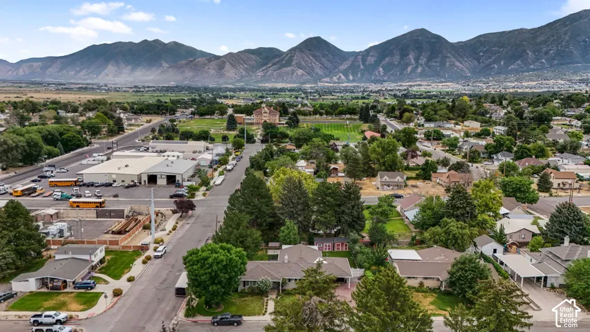 Expansive aerial perspective showcasing a residential neighborhood with surrounding commercial buildings and a prominent mountainous backdrop