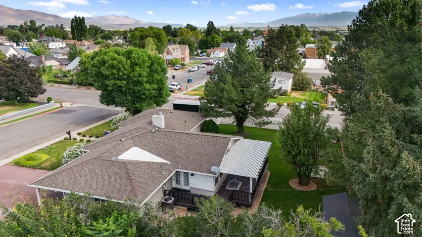 Expansive residential property featuring a large backyard, covered deck, mature trees, and a shingle roof