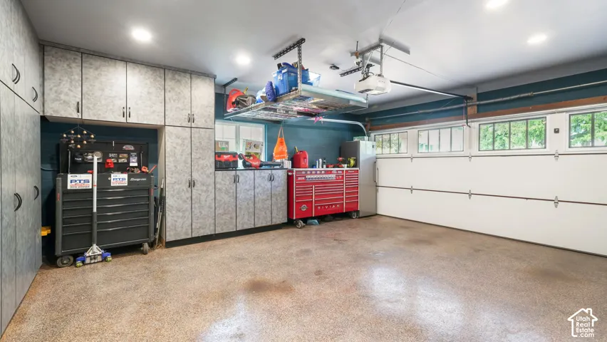 Garage featuring extensive built-in cabinetry, epoxy flooring, overhead storage, and a garage door with transom windows