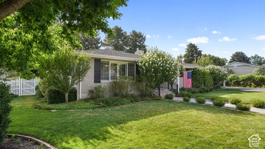 Gray brick exterior featuring black louvered shutters and a white picket fence