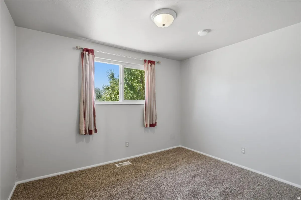 Carpeted interior space featuring a double-paned window, neutral wall paint, and white trim