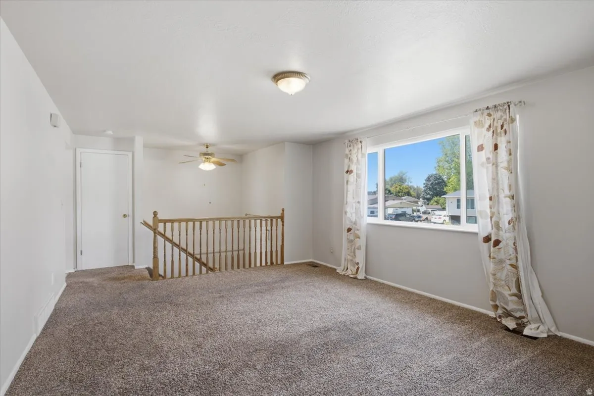 Carpeted living area with light gray walls, a white ceiling, and a large window