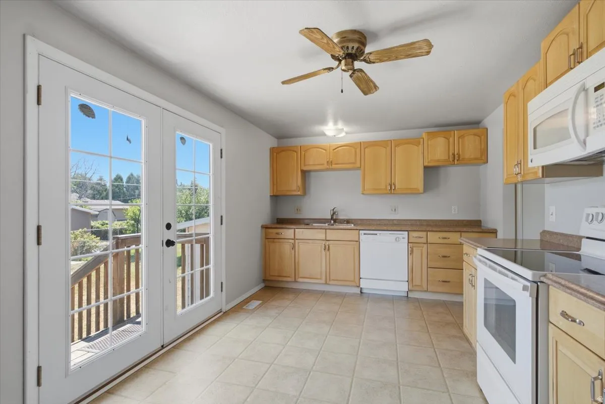 Kitchen featuring light wood-finish cabinetry, tile flooring, and white appliances