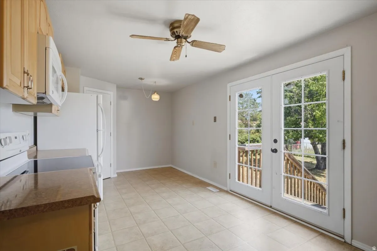 Kitchen area featuring tile flooring, light wood cabinetry, and a countertop with integrated sink