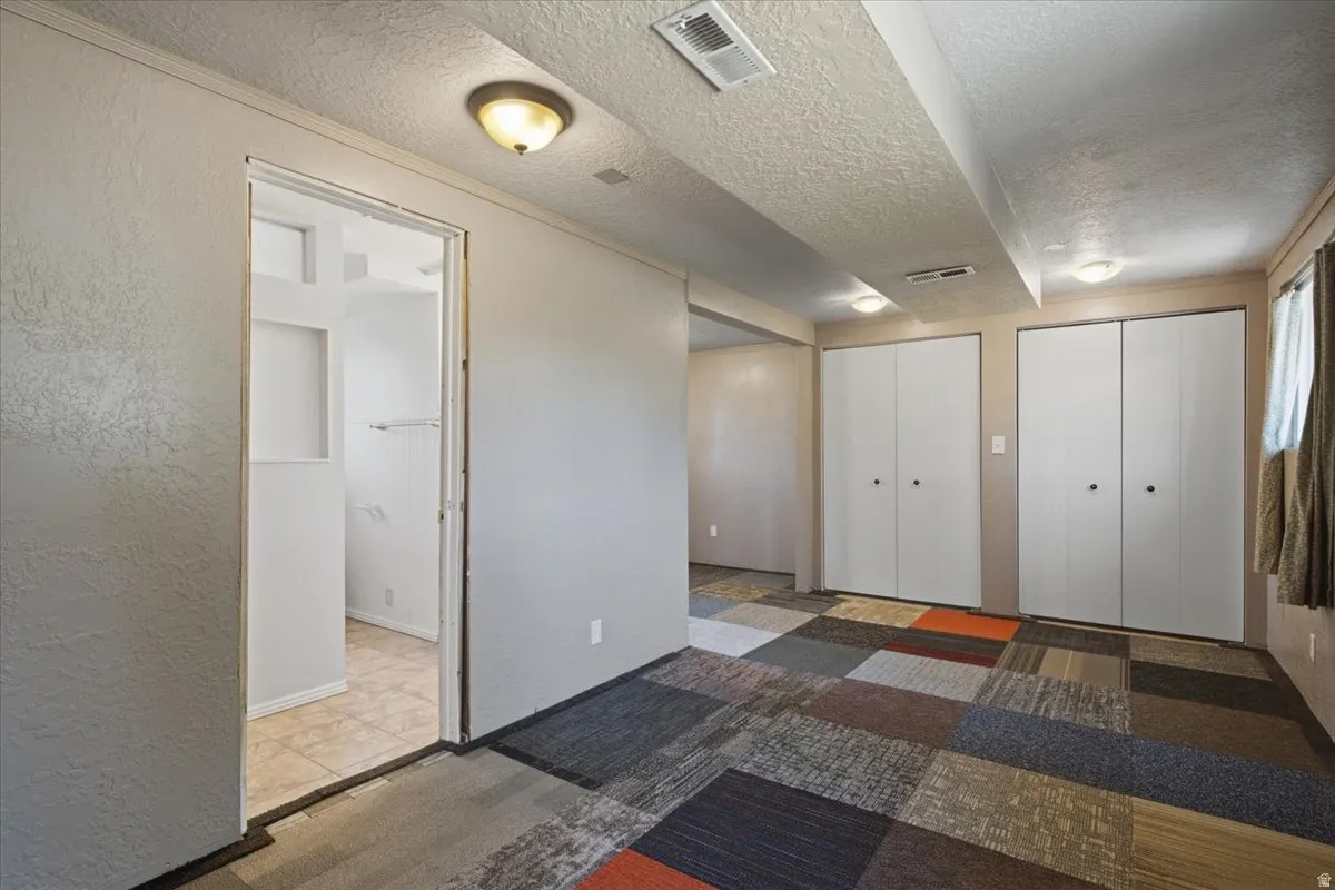 Interior space featuring multi-colored carpet tiles, two white bi-fold closet doors, and recessed ceiling lighting