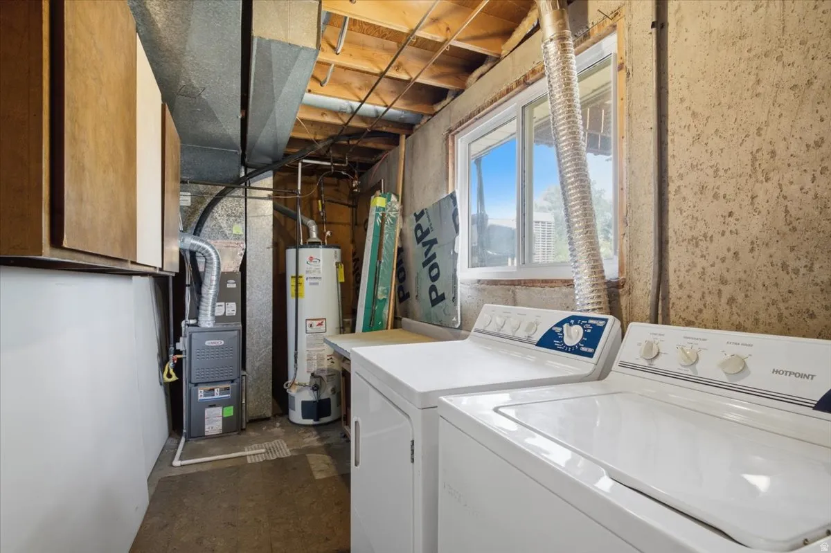 Utility room featuring a window, exposed ceiling joists, and a hot water heater