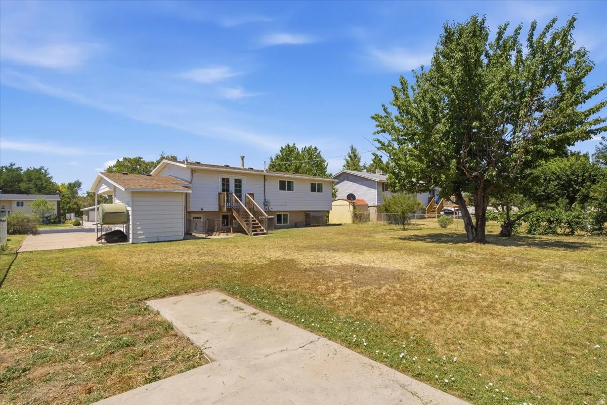 Expansive rear yard featuring mature trees and a concrete patio