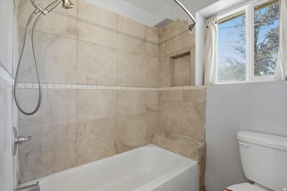 Bathtub and shower combination featuring tiled surround, a recessed shower niche, and brushed nickel fixtures