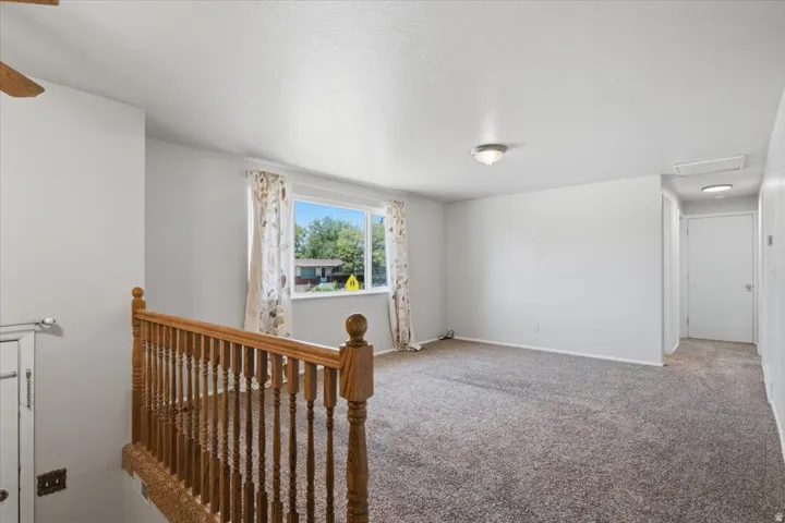 Carpeted room with a wooden railing and balusters