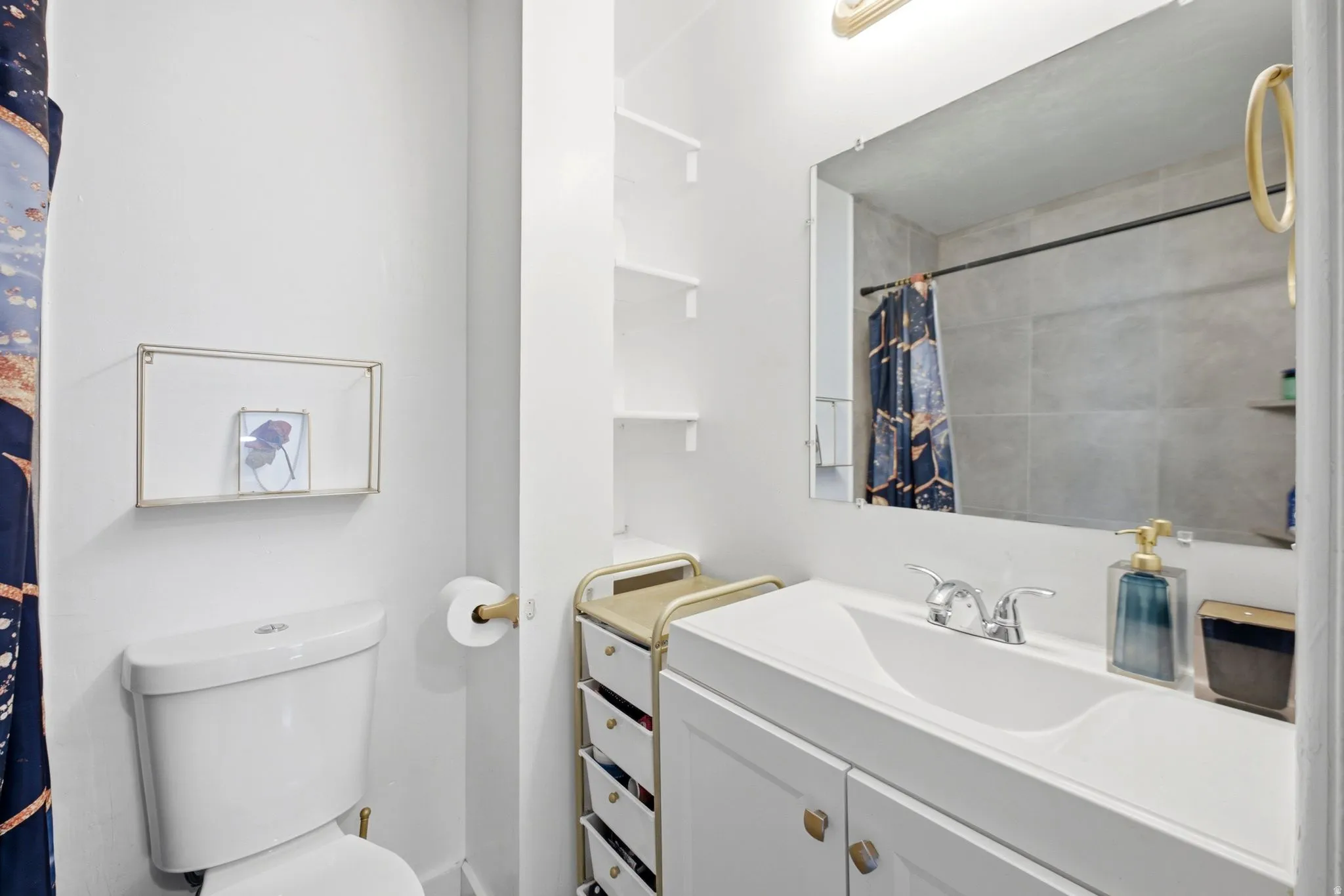Bathroom featuring a white vanity with integrated sink, chrome faucet, and a large mirror
