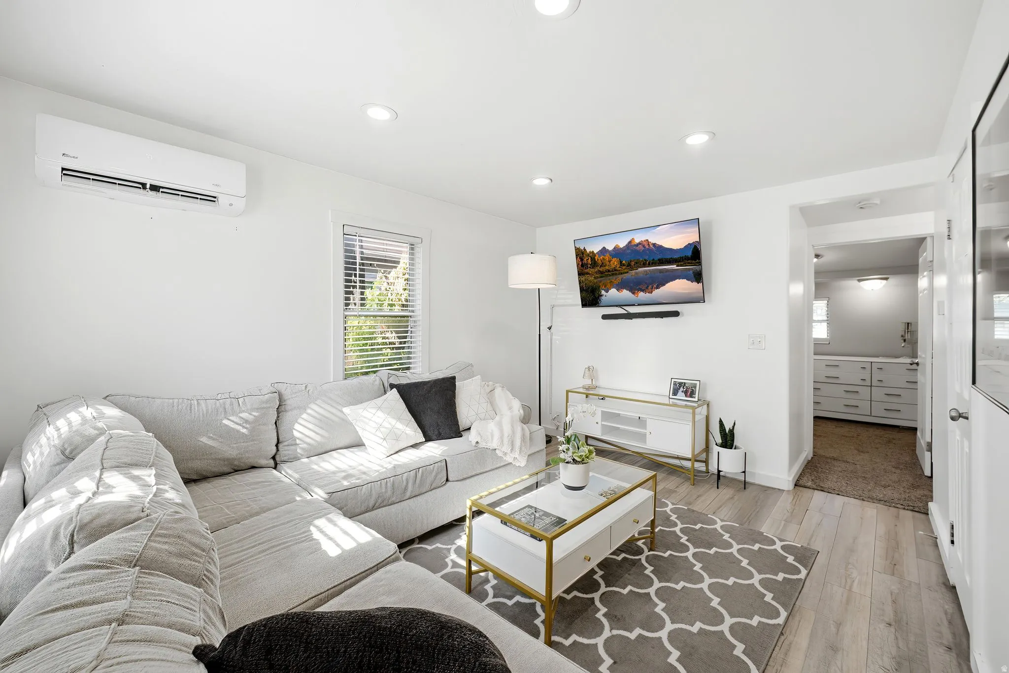Bright living area featuring wood-finish flooring, recessed lighting, and a wall-mounted mini-split AC unit