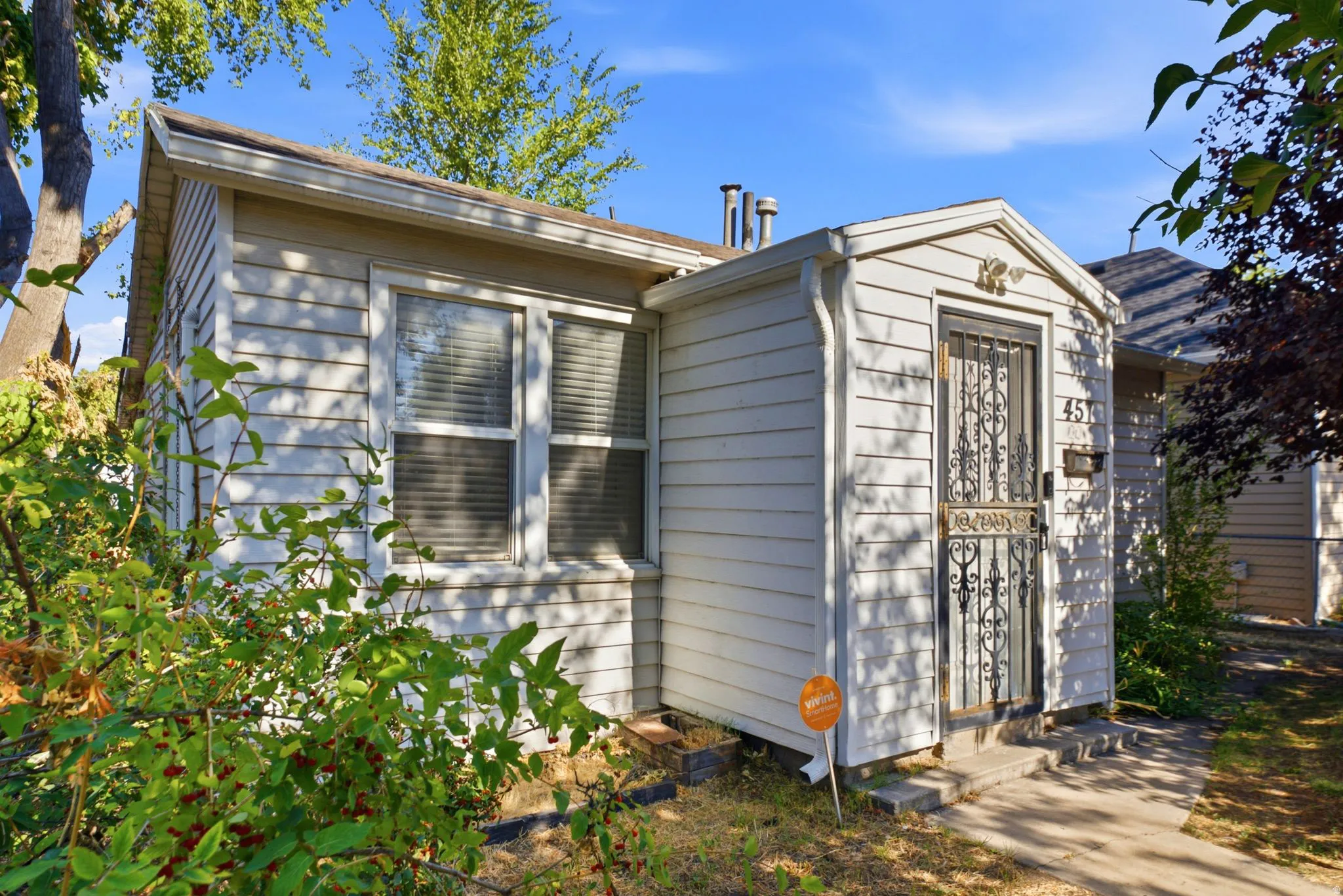 White siding exterior featuring multiple windows and a front entry with a decorative security door