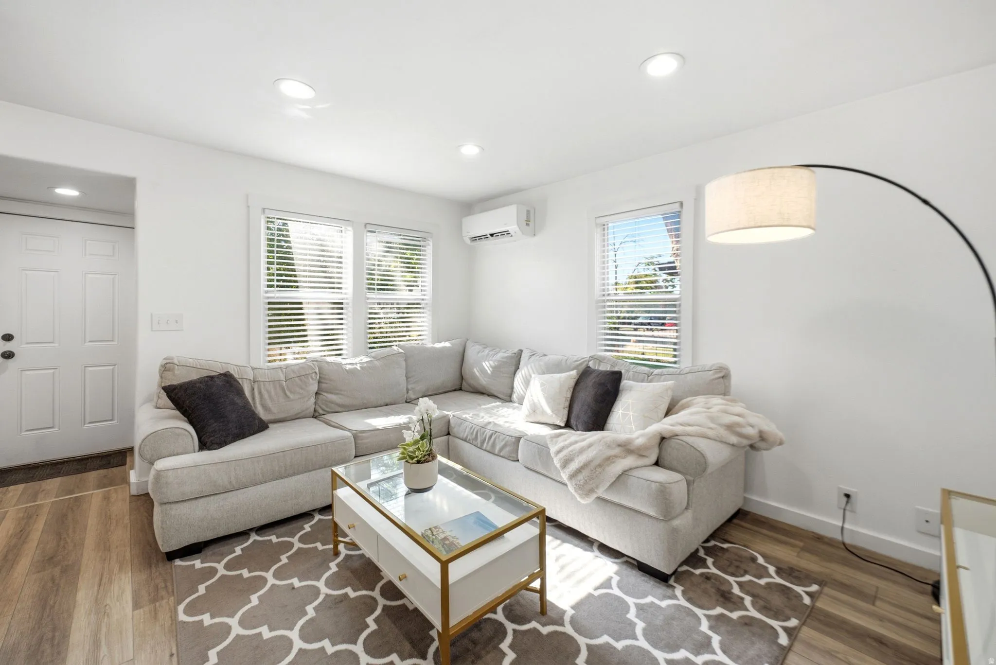 Living area featuring wood-finish flooring, recessed lighting, and white walls