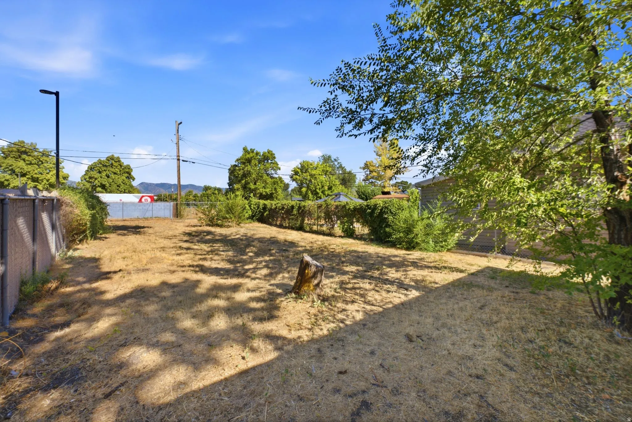 Expansive lot featuring a large open area, perimeter fencing, and mature trees