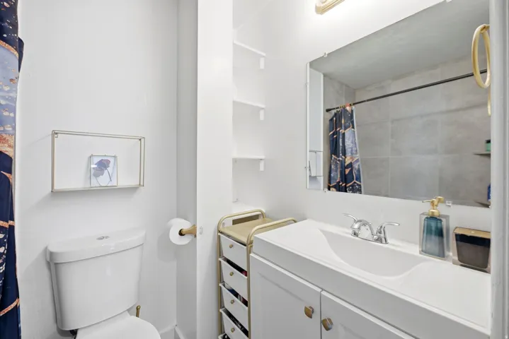 Bathroom featuring a white vanity with integrated sink, chrome faucet, and a large mirror