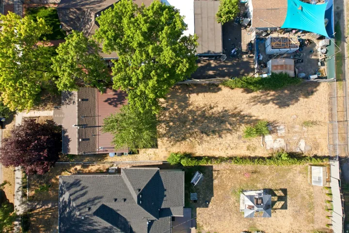 Expansive lot featuring mature trees, a detached structure with a dark shingled roof, and an open pergola
