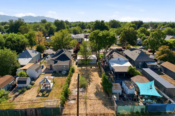 Expansive property featuring a substantial land parcel, mature trees, mountain backdrop, and surrounding residential structures