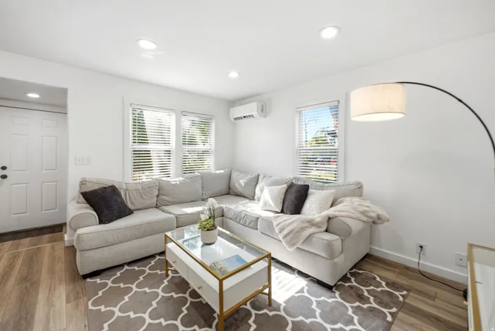 Living area featuring wood-finish flooring, recessed lighting, and white walls