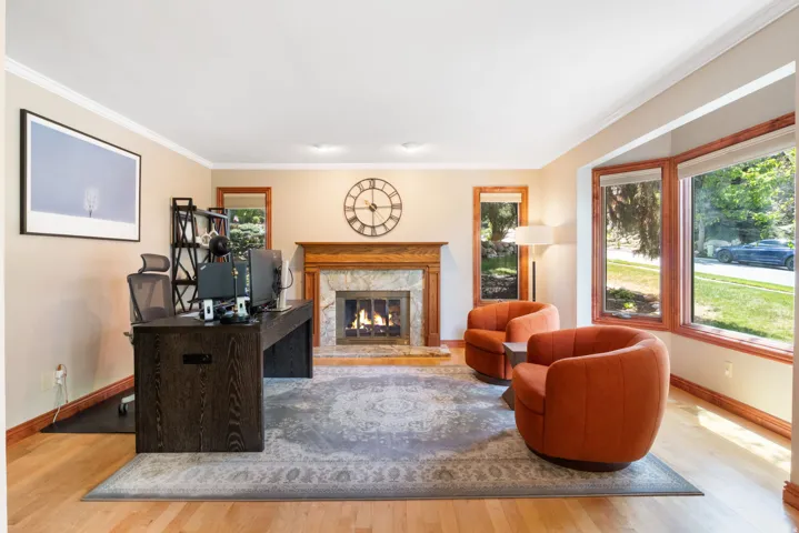 Formal living space featuring a wood-burning fireplace with a marble surround and a carved wood mantel