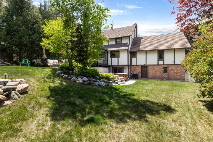 Multi-level rear exterior featuring a brick foundation and white siding with dark trim accents