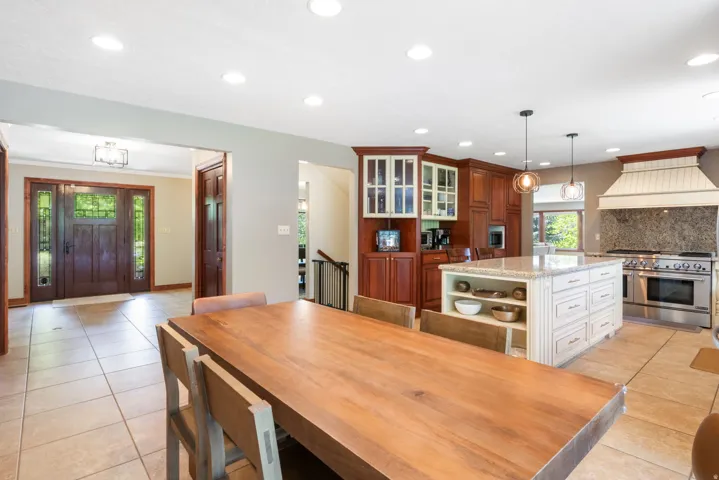 Spacious kitchen and dining area with a large center island, built-in cabinetry, stainless steel range, and tile flooring