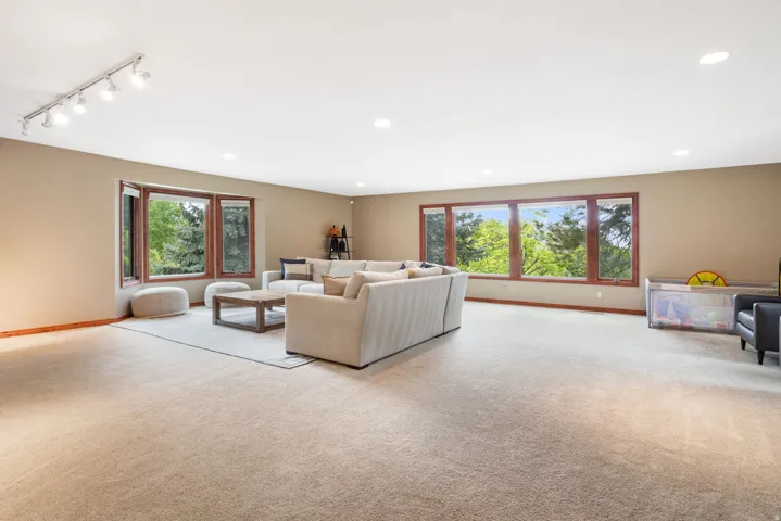 Spacious living area featuring extensive carpeting, recessed lighting, and a track lighting fixture