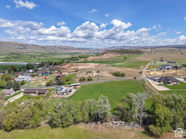 Expansive landscape featuring distant mountains, verdant fields, and scattered residential properties
