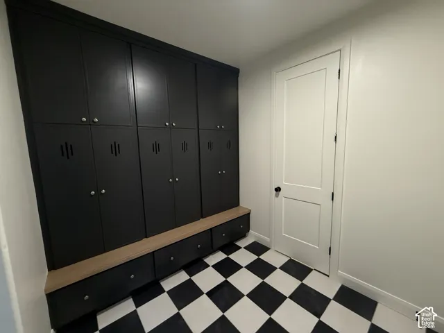 Built-in black cabinetry with silver hardware, wood-finish bench seating, black and white checkerboard flooring, and a white interior door with black hardware