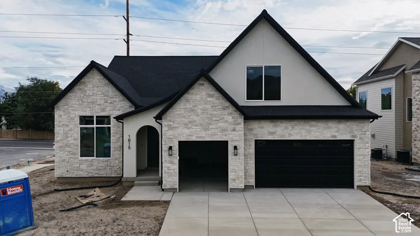 Newly constructed facade featuring light-toned stone veneer and dark asphalt shingles