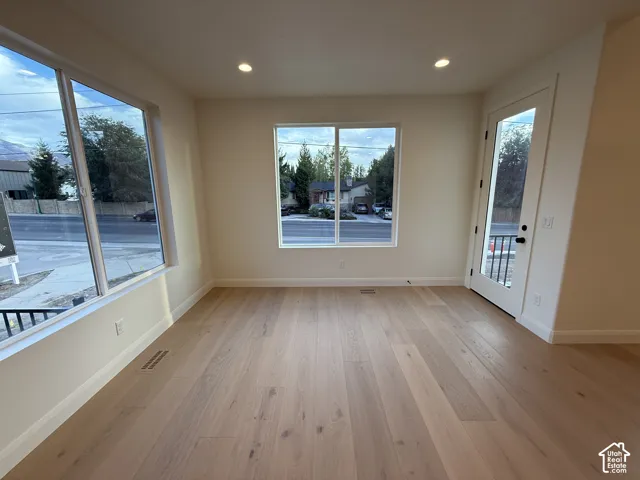Light wood-finish flooring, recessed lighting, multiple windows, and a glass-paneled door