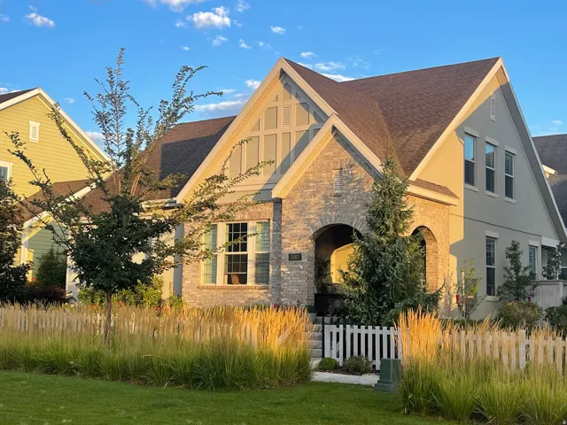 Exterior featuring a brick and stucco facade, an arched entryway, gabled rooflines, and a picket fence