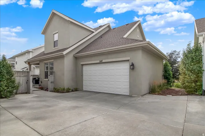 Stucco exterior with a peaked roofline, an attached two-car garage, and a concrete driveway