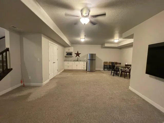 Recessed lighting, wood-finish flooring, white cabinetry, stainless steel refrigerator, and ceiling fan