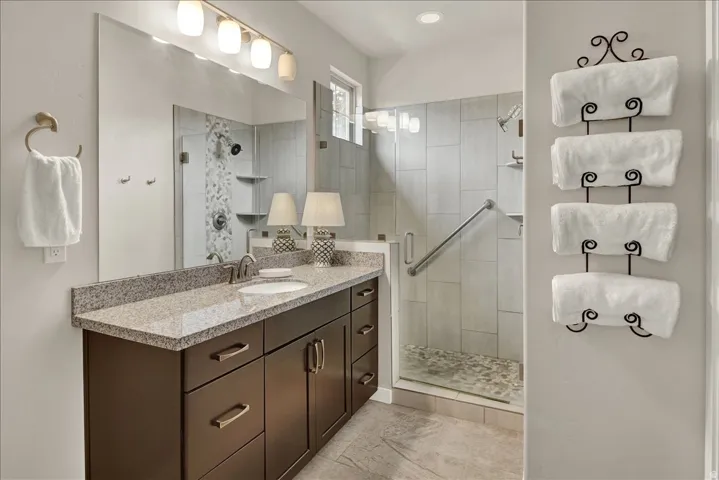 Bathroom vanity featuring a light granite countertop with an integrated sink and dark wood-finish cabinetry