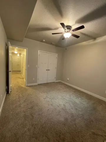 Ceiling fan with integrated lighting, recessed ceiling feature, light gray wall paint, white trim, and carpet flooring
