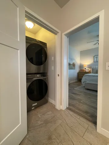 Dedicated laundry closet with stacked appliances and overhead lighting