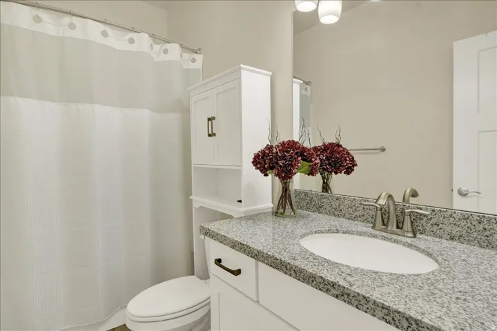 Bathroom featuring a spacious vanity with granite countertop, integrated sink, and brushed nickel faucet