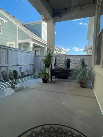 Covered patio with polished concrete flooring, mature landscape plantings in decorative containers, and overhead shade structure