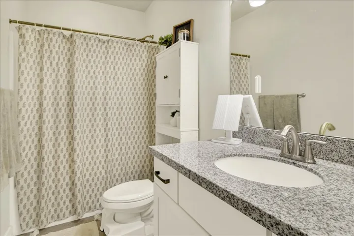 Vanity with granite countertop, integrated sink, and brushed nickel faucet