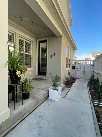 Covered porch entry featuring a stucco exterior and concrete walkway