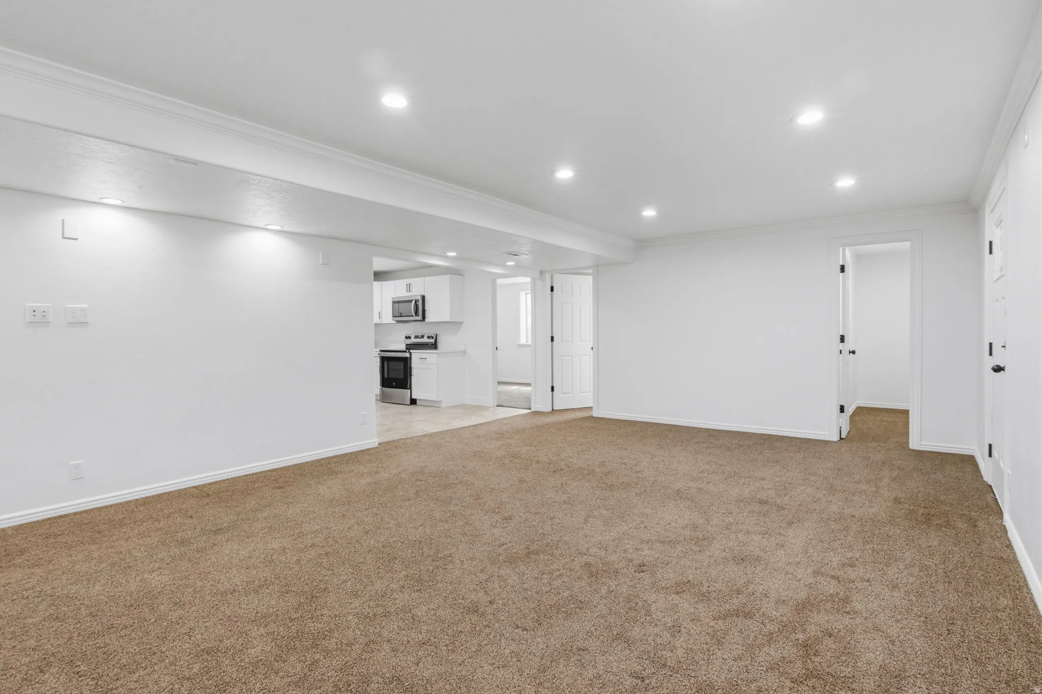 Spacious room with plush carpeting, recessed lighting, white walls, and crown molding