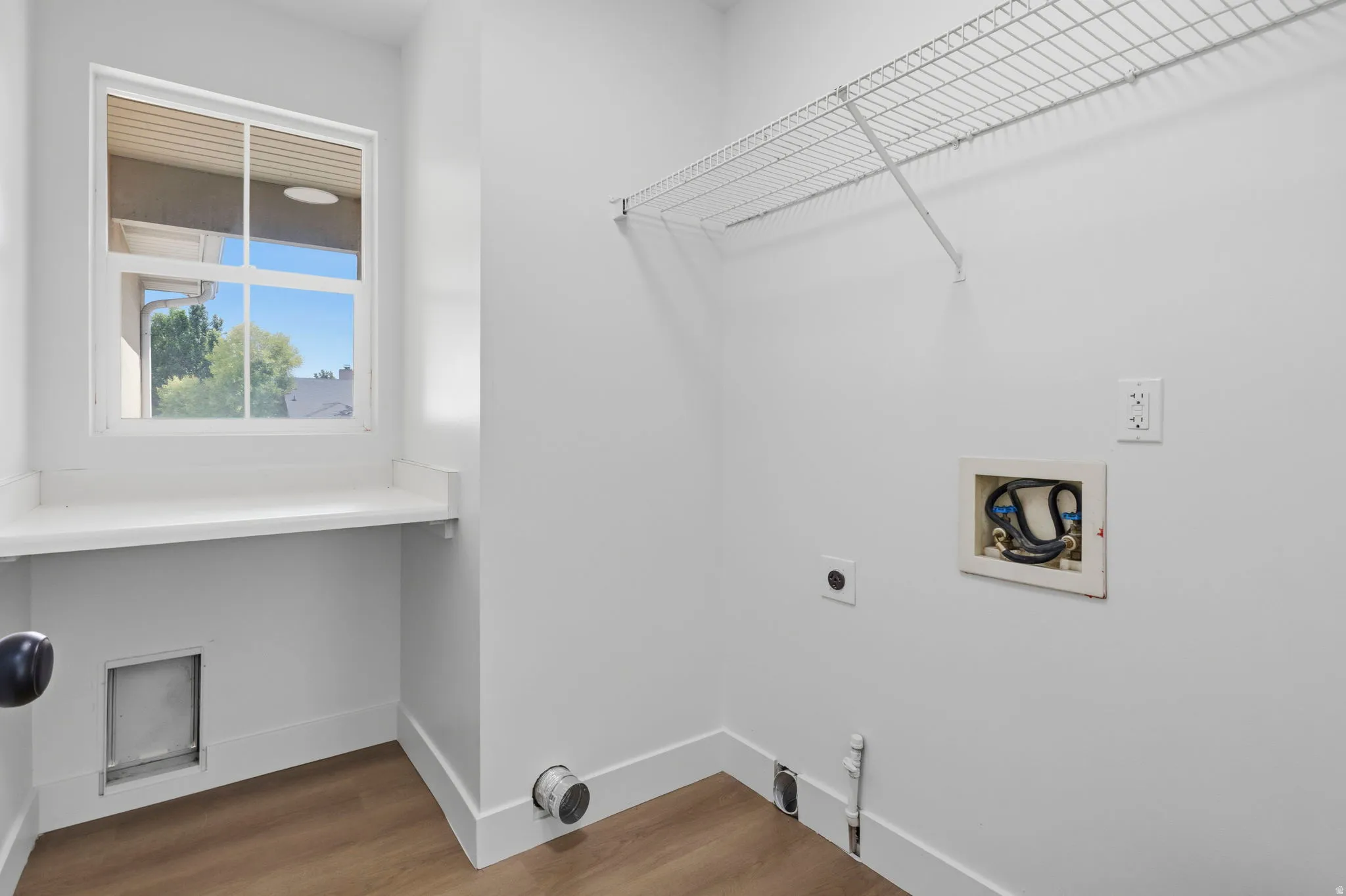 Laundry area featuring wood-finish flooring and white walls