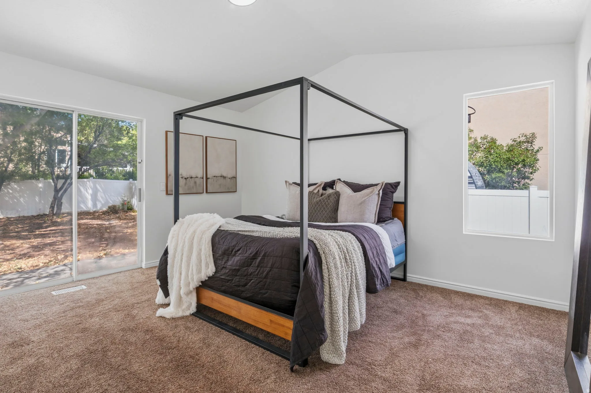Spacious interior with vaulted ceilings, plush carpeting, and a glass sliding door leading to an outdoor area