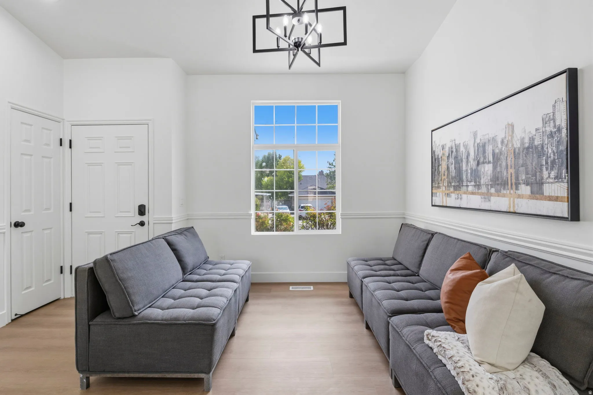 Bright room featuring wood-finish flooring, white paneled doors, and a decorative ceiling light fixture