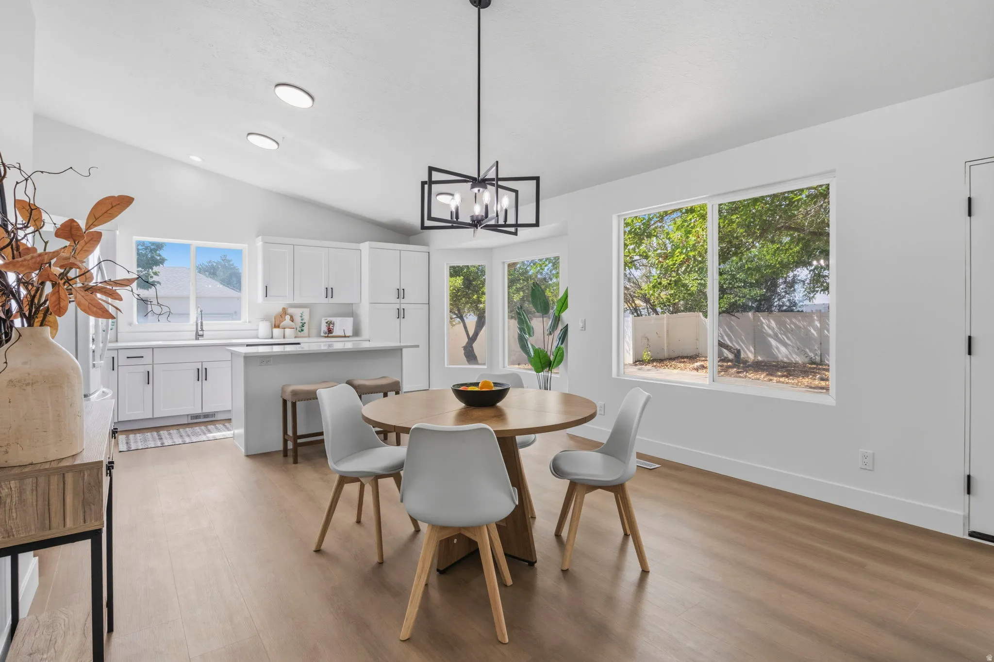Open-concept living space with wood-finish flooring, white walls, and a vaulted ceiling