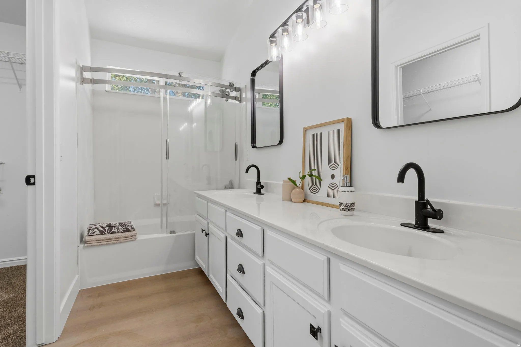 Bathroom featuring a dual vanity with white cabinetry, matte black hardware, and stone-finish countertops