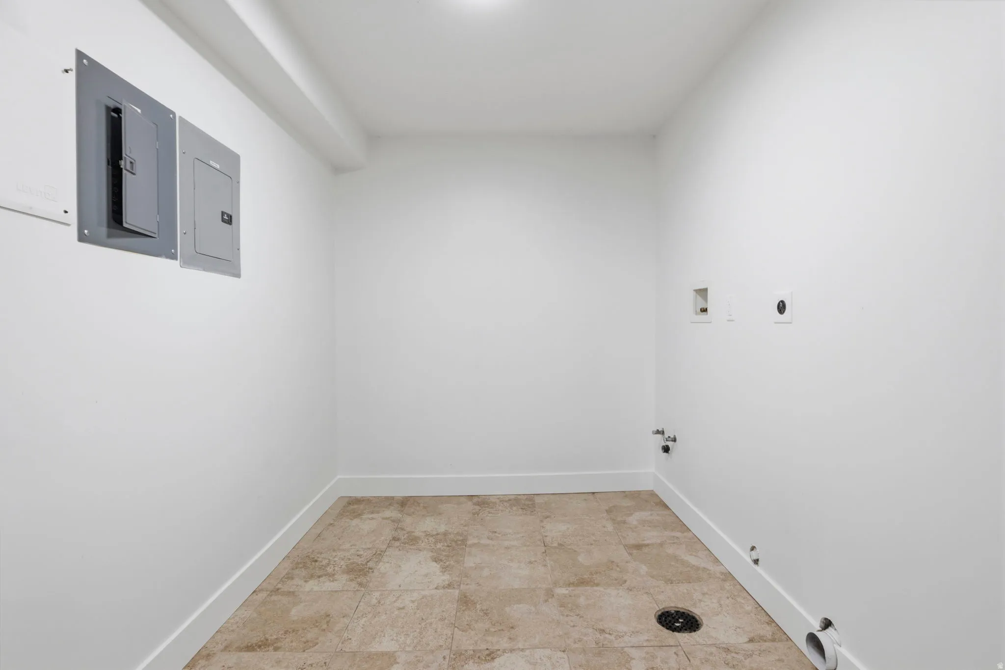 Utility room featuring neutral-toned floor tile and white baseboards
