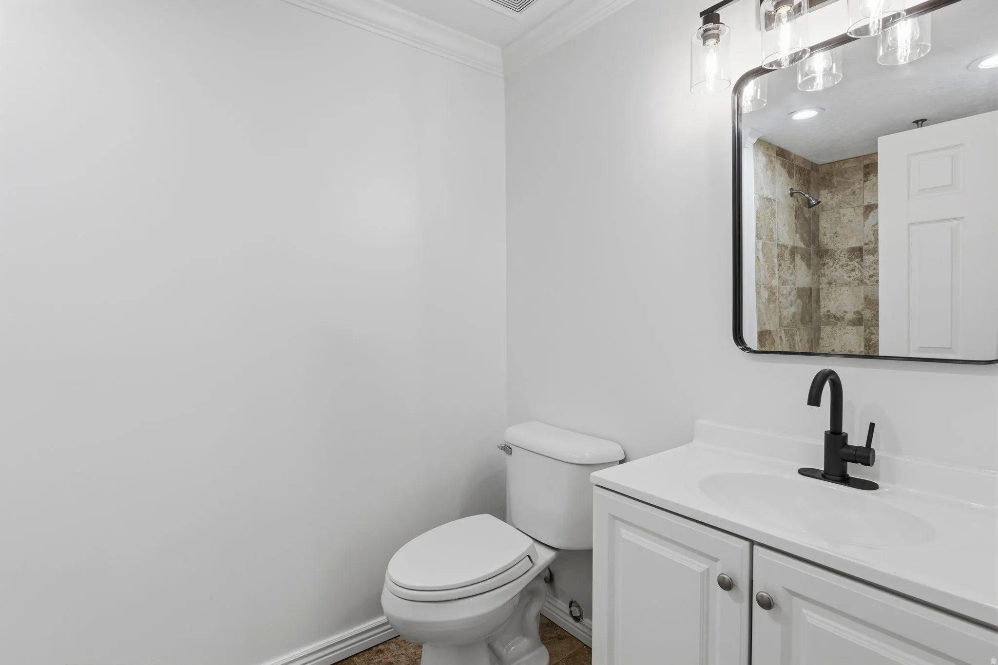 Bathroom featuring a white vanity with integrated sink, matte black faucet, and a rectangular mirror with a black frame
