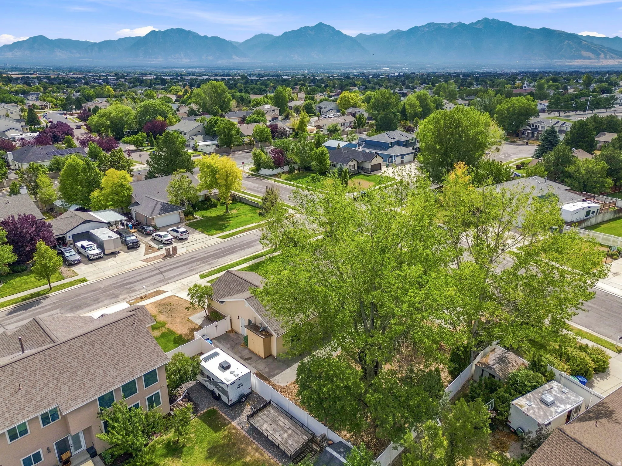 Expansive suburban neighborhood featuring mature trees, paved streets, and distant mountain ranges